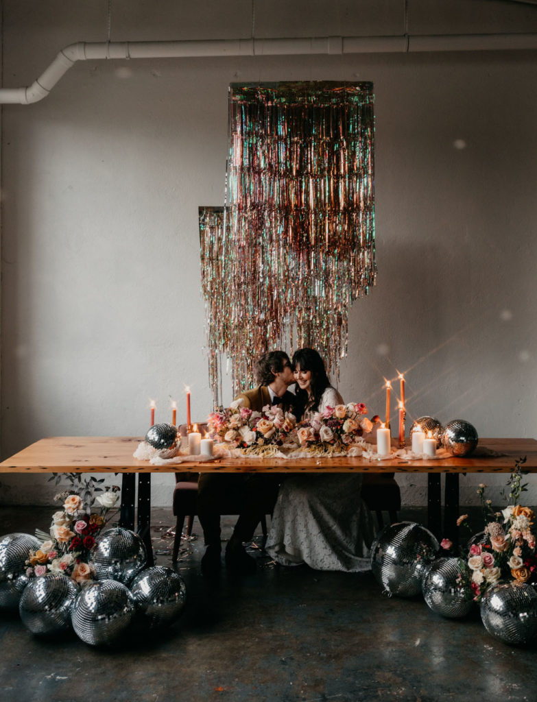bruidspaar aan tafel met discoballen decoratie photography- Lauren Miles Photo